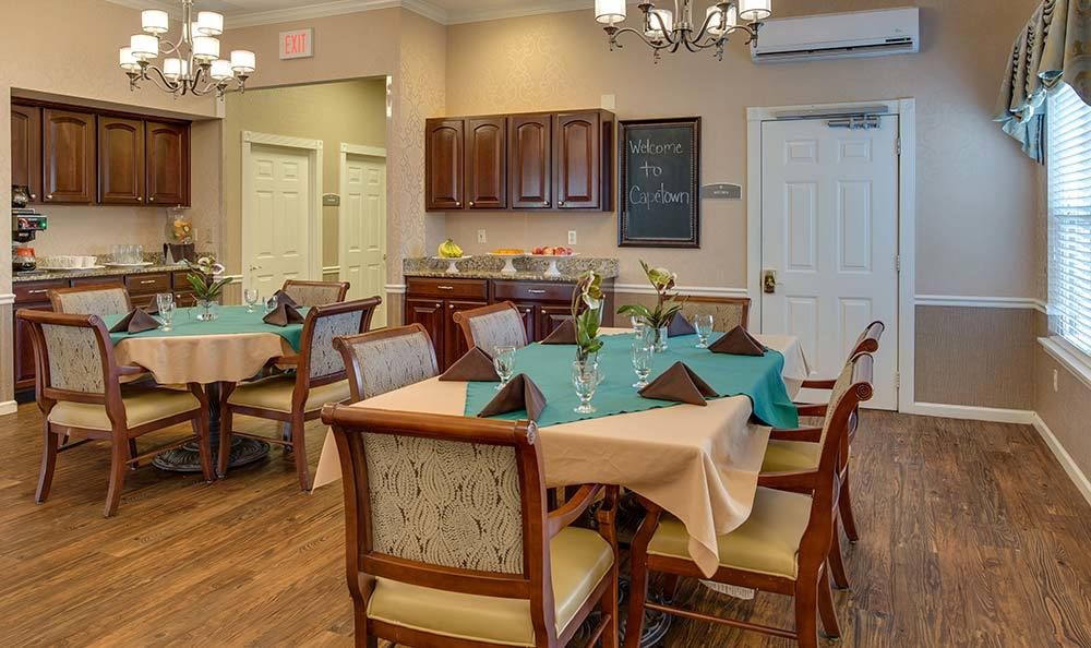 A cozy dining area with set tables, wooden furniture, and warm lighting.