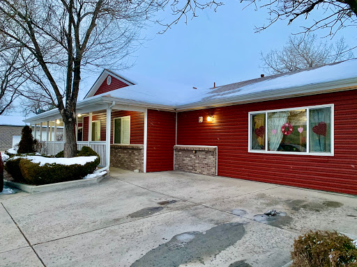 A cozy red home during the winter season, surrounded by snow and trees.