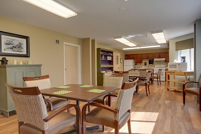 A spacious community dining and kitchen area with tables, chairs, and ample lighting.