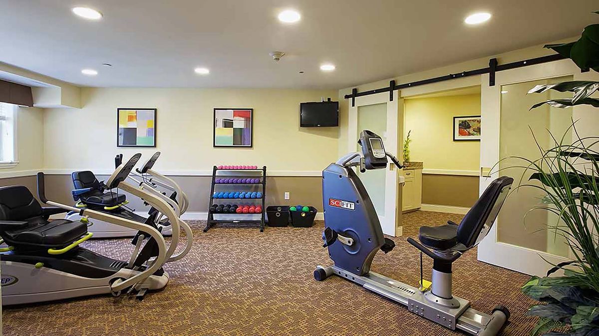 A small gym with exercise equipment including stationary bikes and a rack of dumbbells.