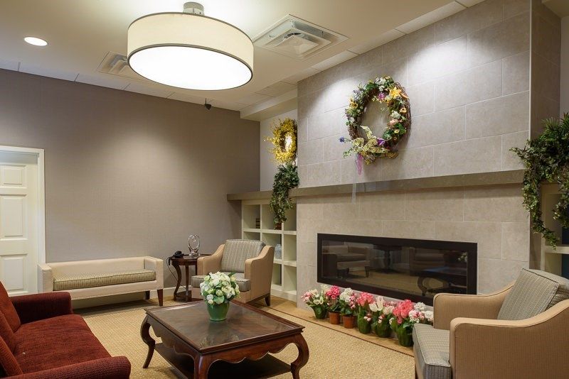 A cozy living room with elegant furniture and decorative elements, including a wreath and flowers by the fireplace.