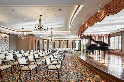 A sophisticated auditorium featuring an elegant stage with a piano and rows of chairs, perfect for performances or events.
