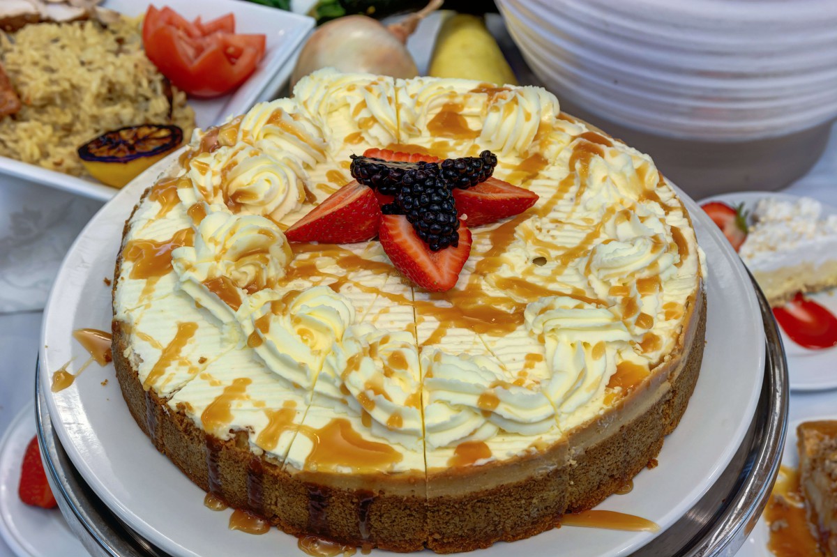 A delicious cake topped with fresh strawberries, blackberries, and drizzled with caramel.