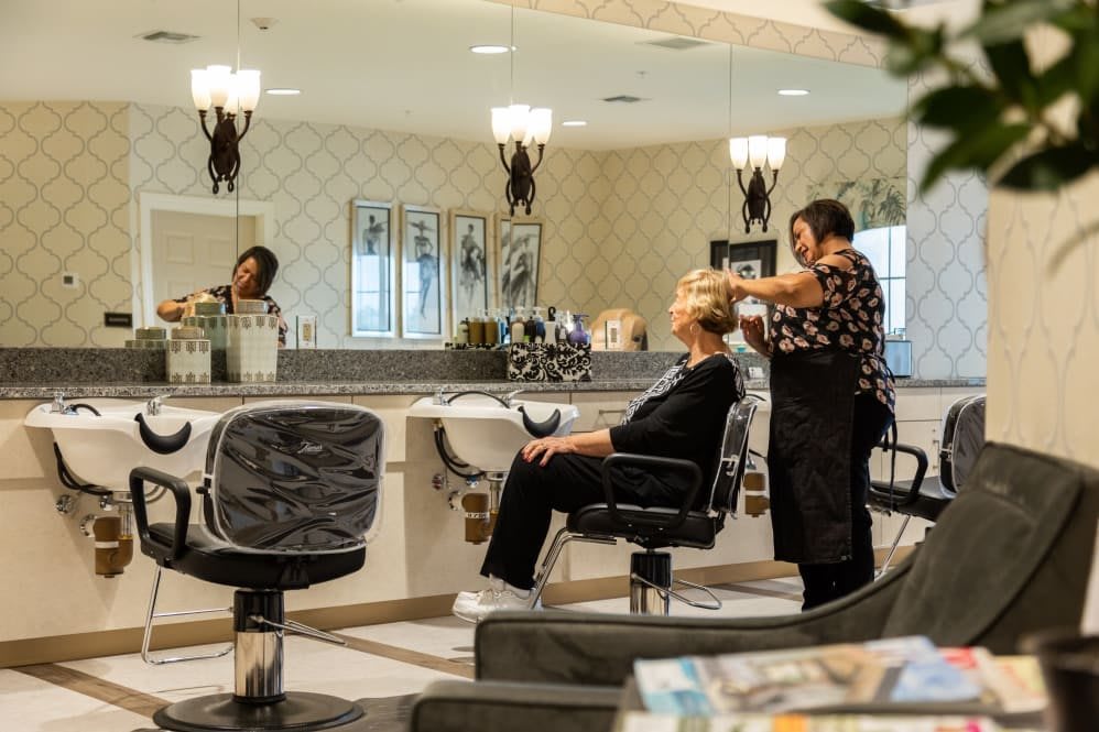 A hairstylist working on a customer's hair in a well-lit salon.