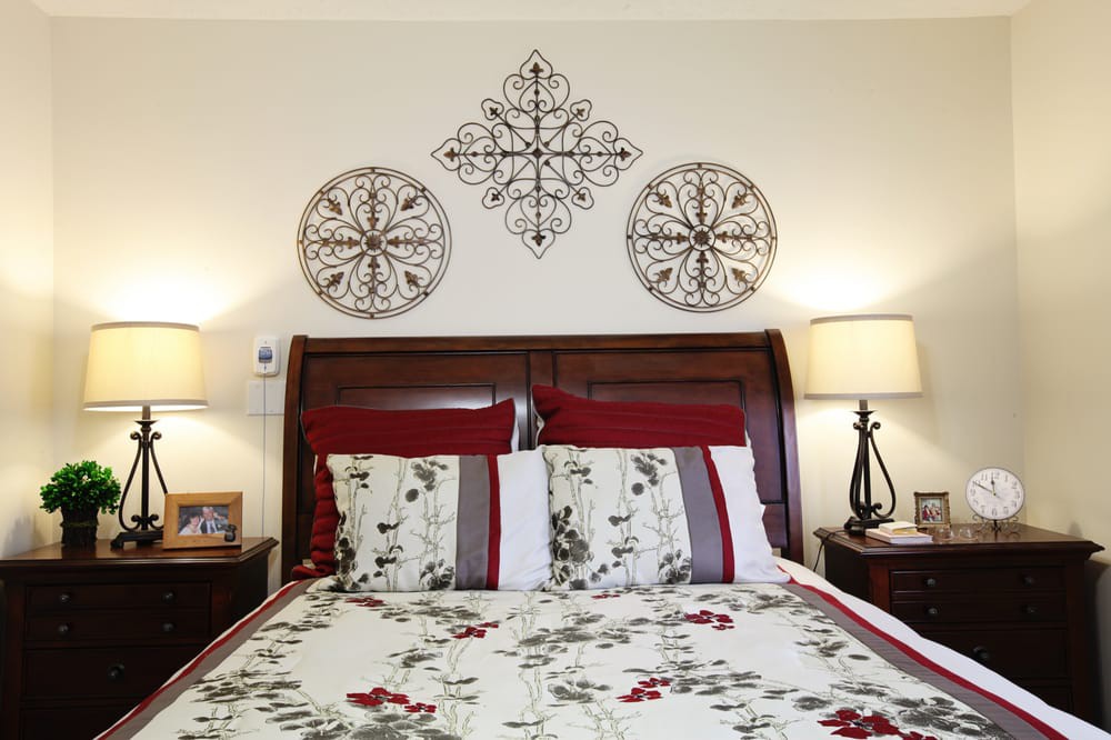 A cozy bedroom featuring floral bedding, elegant wall art, and warm lighting from bedside lamps.