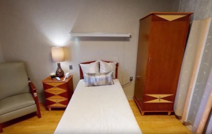 A cozy bedroom with a single bed, nightstand, and wardrobe.