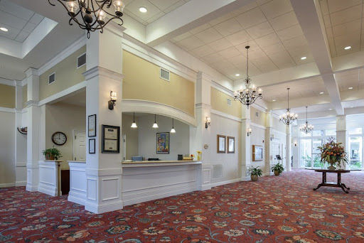 A spacious and elegantly designed hotel lobby featuring a reception desk, chandeliers, and decorative carpet.
