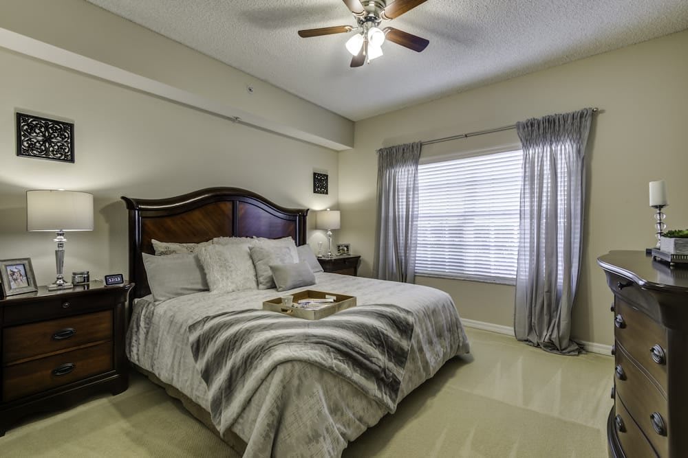 A cozy bedroom with a large bed, elegant bedding, and natural light streaming through the window.