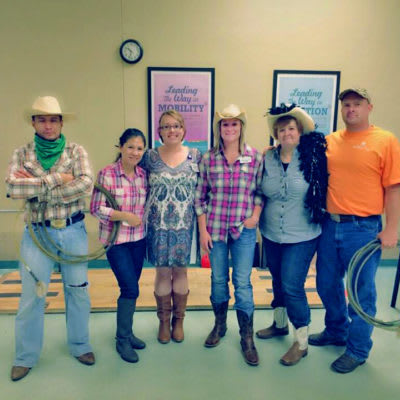 A group of people dressed in cowboy-themed costumes posing together indoors.