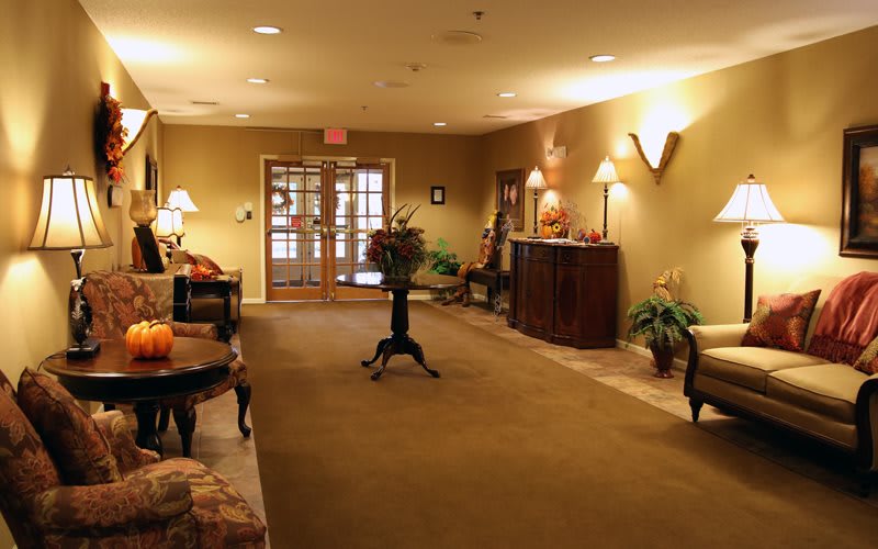A warmly lit lobby area with furniture, plants, and decorative elements.