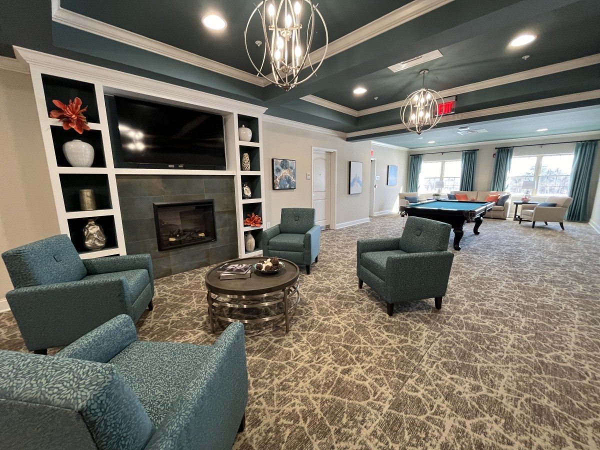 A modern living room with comfortable seating, a fireplace, and a pool table.