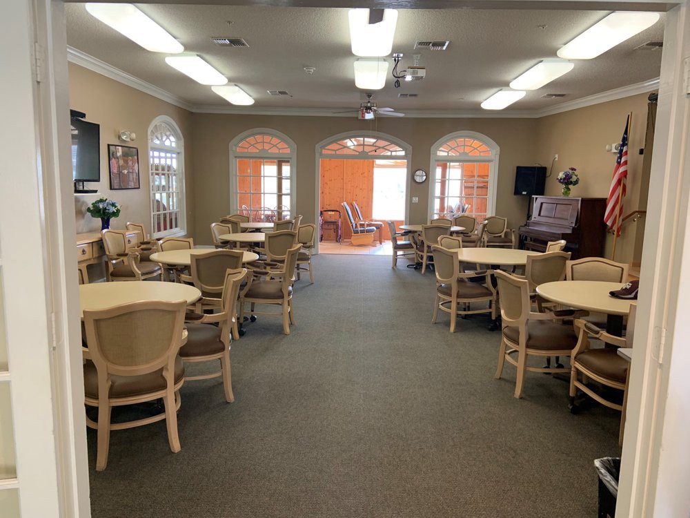 A spacious dining area with multiple tables and chairs arranged neatly under bright lighting.