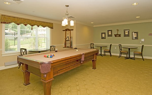 A well-lit game room featuring a billiards table and seating area.