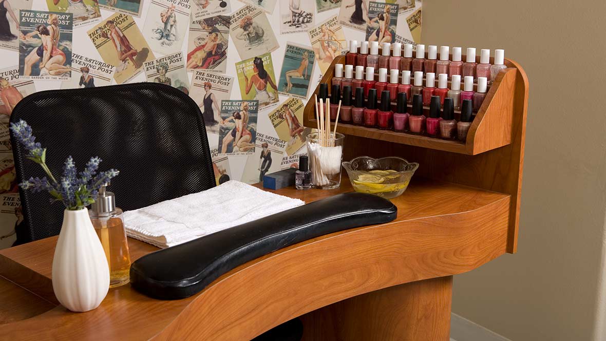 A well-equipped manicure station in a nail salon with a variety of nail polish bottles and stylish decor.