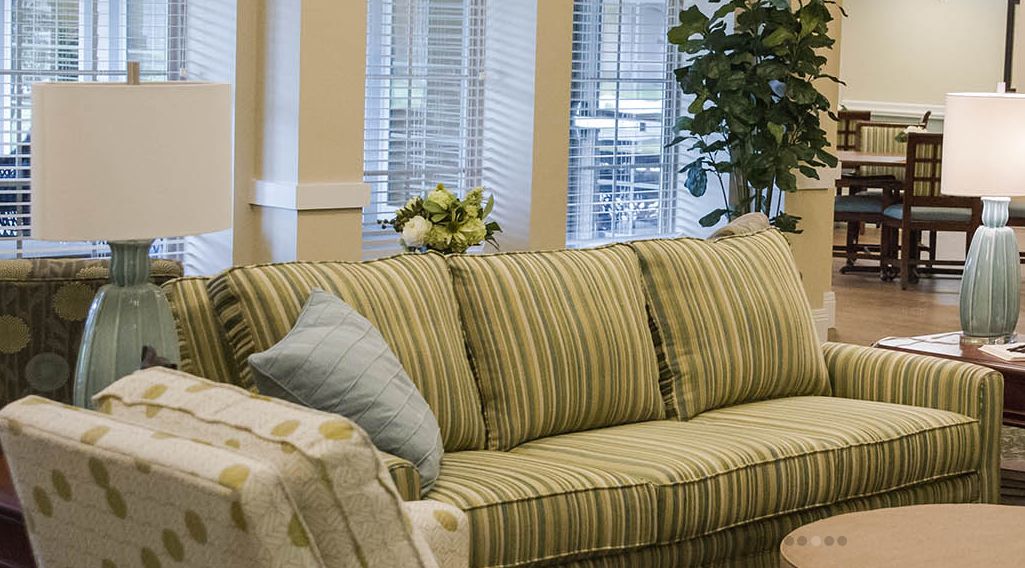 A cozy living room with a striped sofa and decorative cushions in front of a window with blinds.