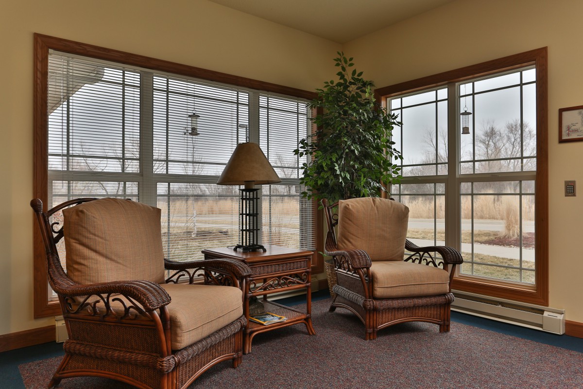 A cozy living room with armchairs and large windows offering a view outside.