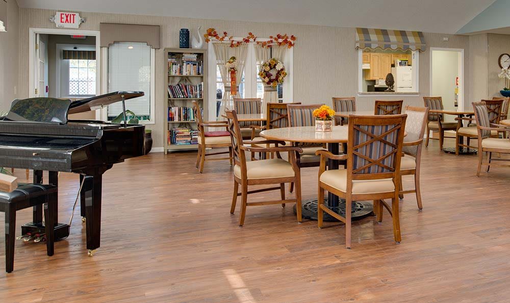 A cozy dining area with a piano, bookshelves, and autumn-themed decorations.