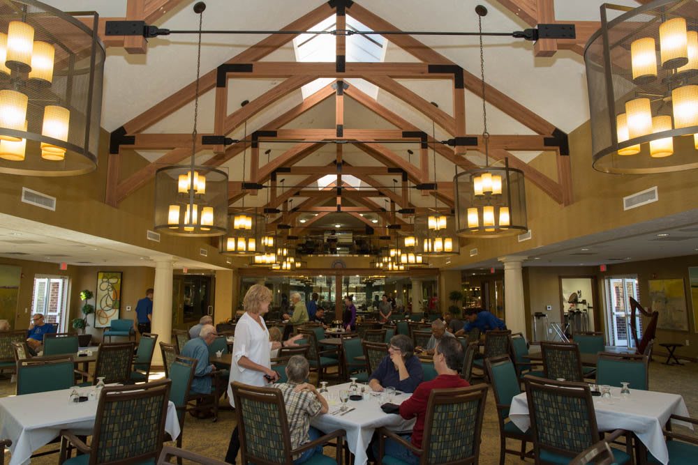 A spacious dining hall with wooden beams, elegant lighting, and patrons enjoying their meals.