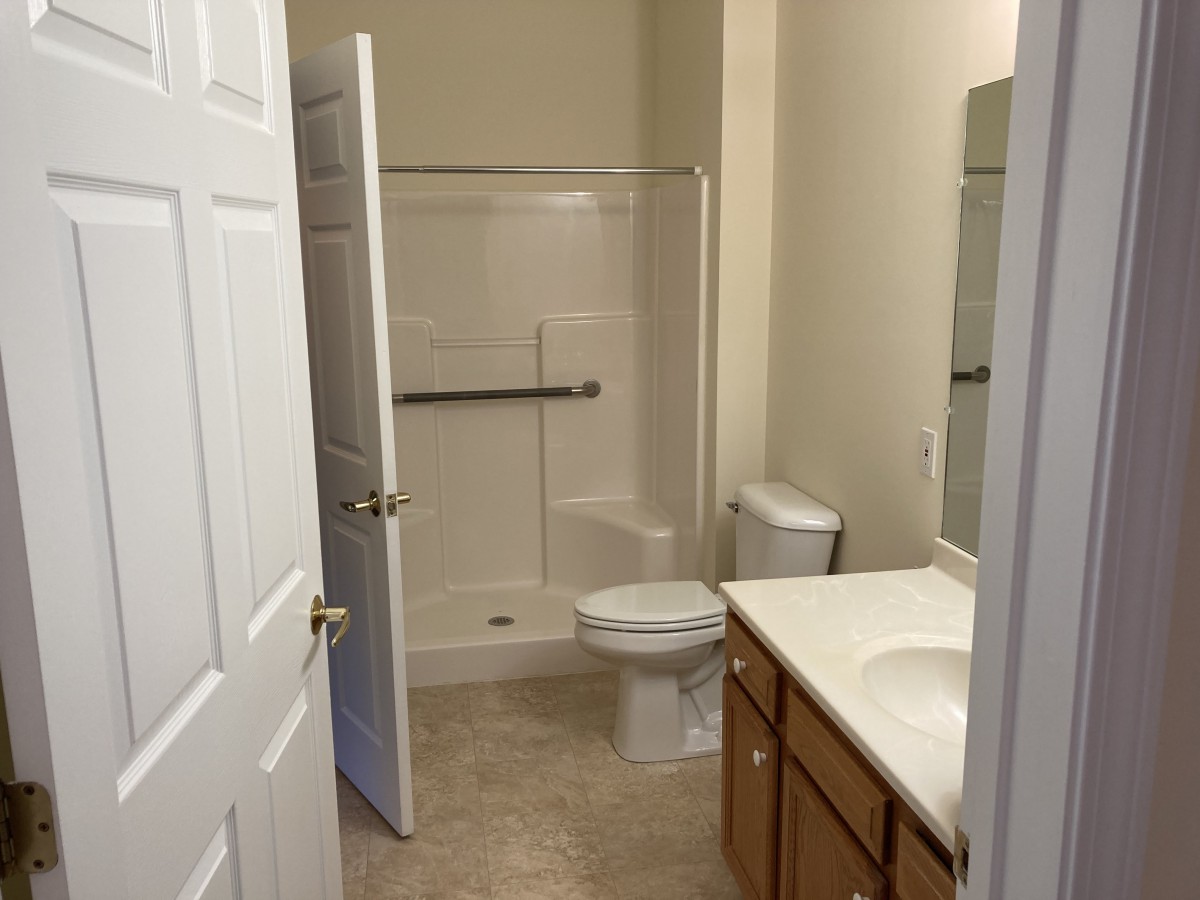 A clean and simple bathroom with a shower, toilet, and sink.
