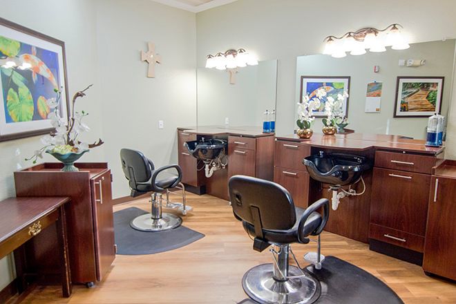 A well-lit and spacious hair salon interior featuring styling chairs, mirrors, and sinks on a wooden floor.