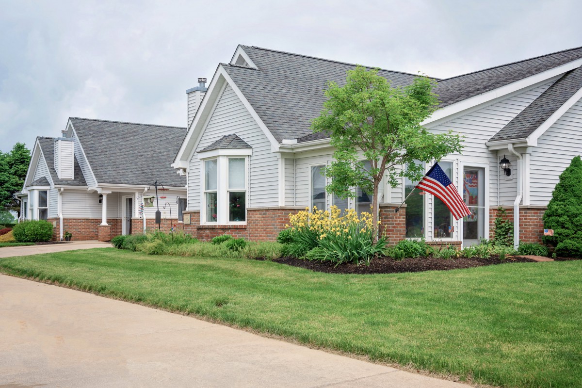 A suburban residential house with a well-maintained yard and an American flag.