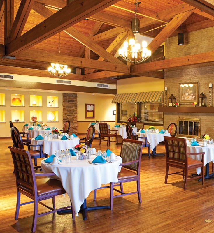 An elegant dining room featuring neatly arranged tables with blue napkins and a warm, inviting ambiance.