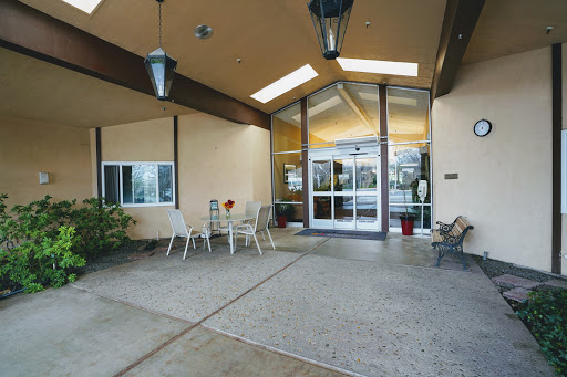 A welcoming entrance to a modern building, featuring outdoor seating and natural light.