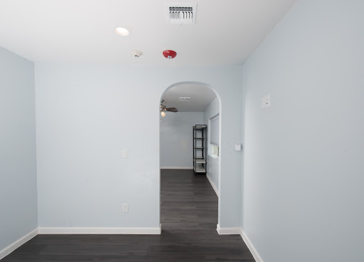 A spacious room featuring light blue walls and an arched doorway, showcasing modern design elements.