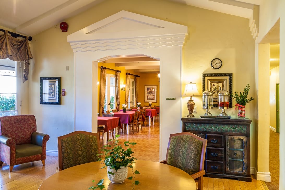 A cozy dining room with elegantly set tables and warm lighting, featuring tasteful decor and plants.