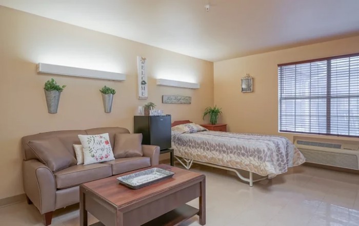 A cozy and well-decorated room with a bed, sofa, and table.