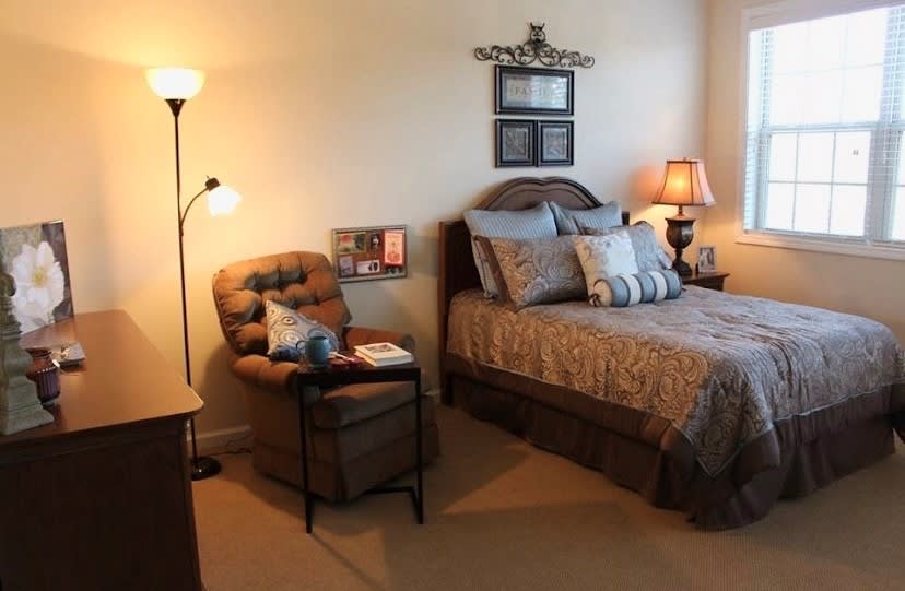 A cozy bedroom with a bed, chair, and decorative lamps.