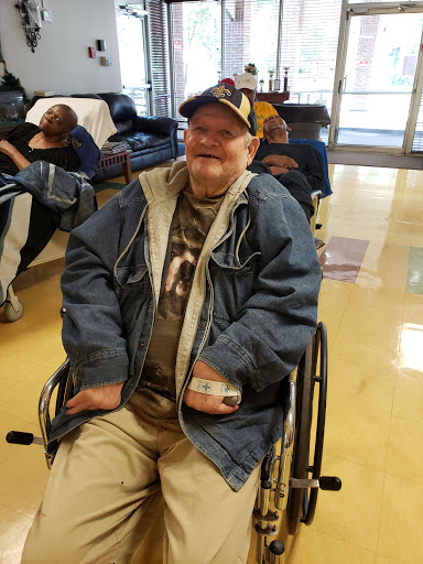 An elderly man enjoying his time in a wheelchair, smiling while dressed casually.
