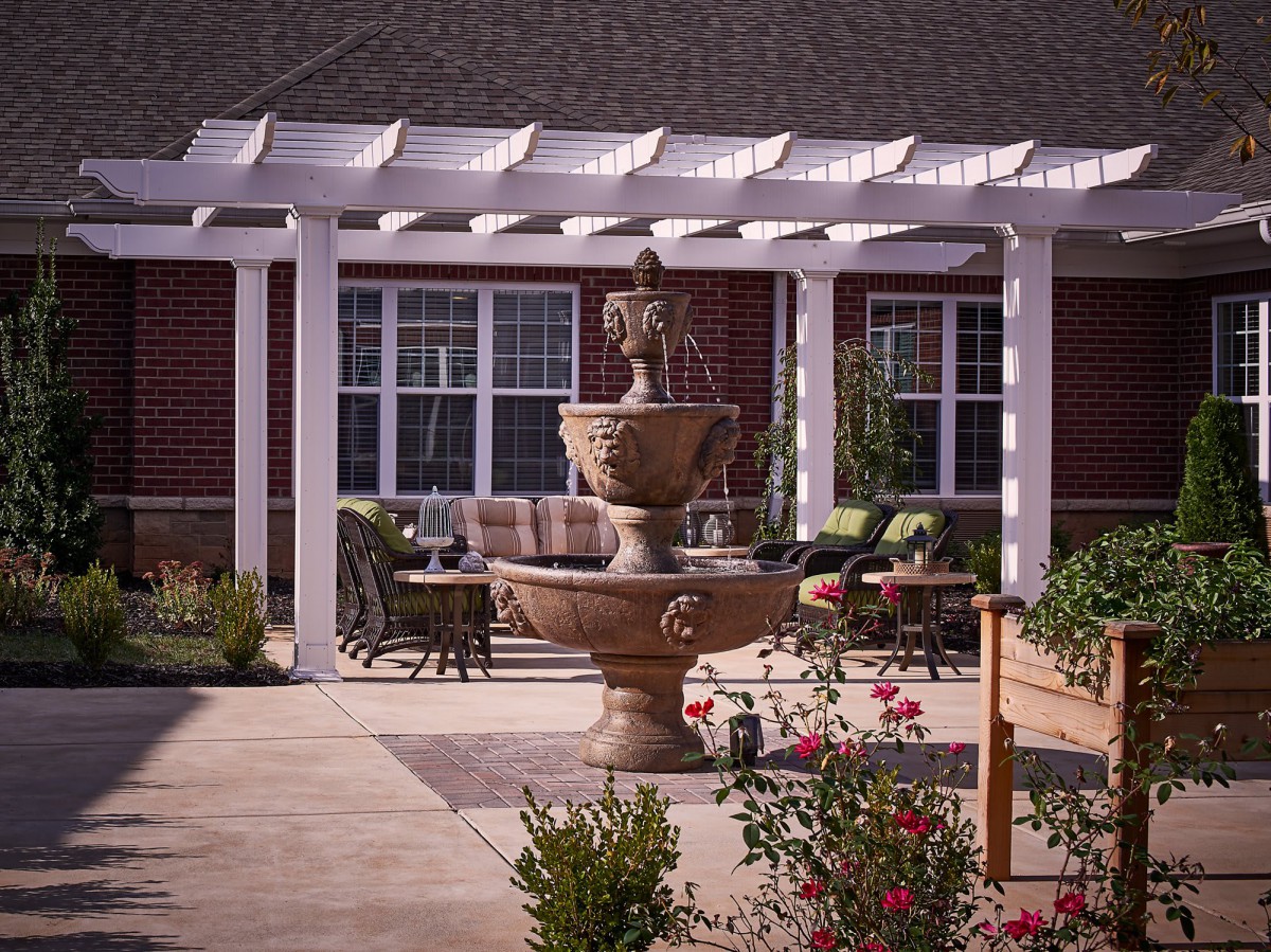 A beautiful courtyard featuring a fountain surrounded by a pergola and garden seating.