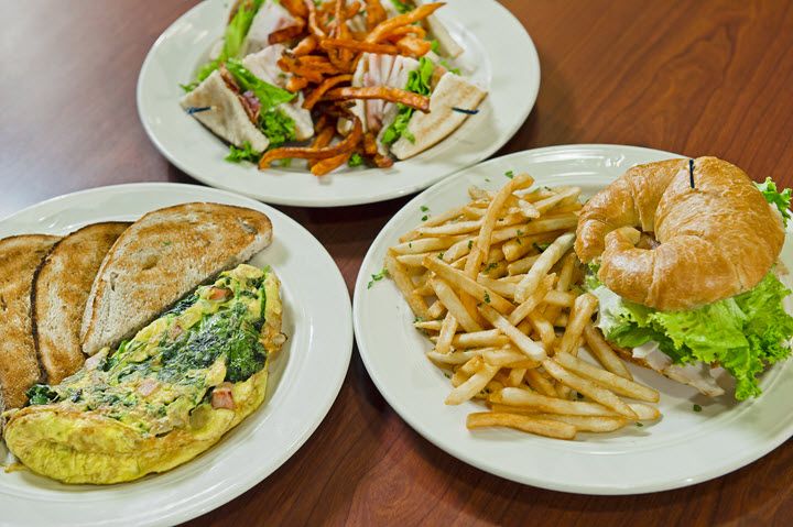 A variety of dishes including an omelette, a sandwich with fries, and a salad.