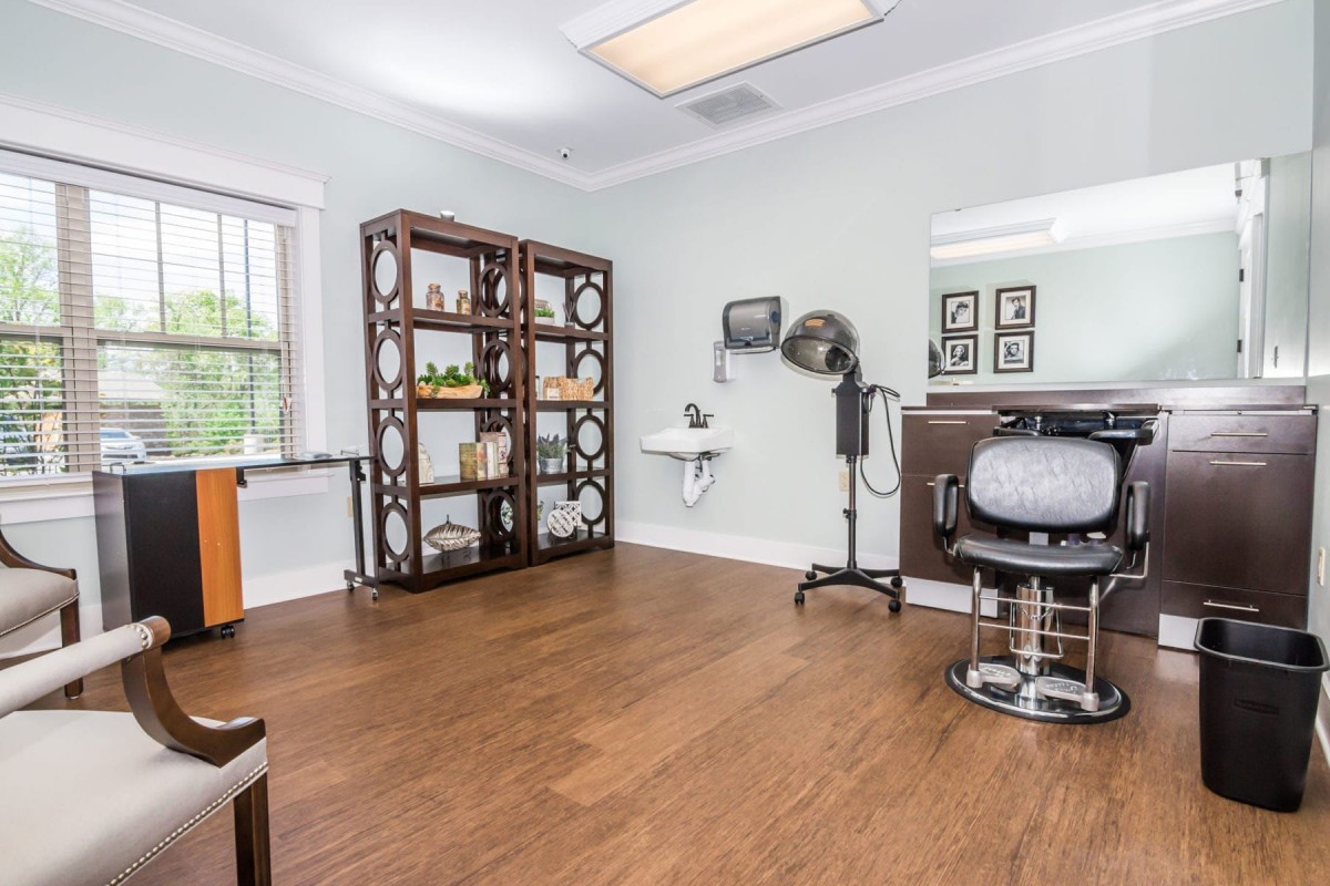A well-lit hair salon with a styling chair, mirror, and various hair equipment.