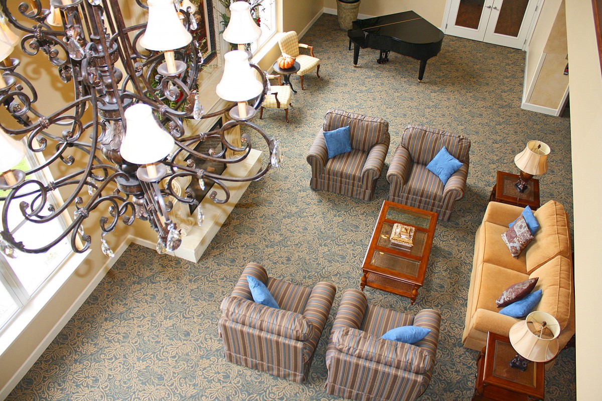 A hotel lobby with comfortable seating, a chandelier, and a grand piano.