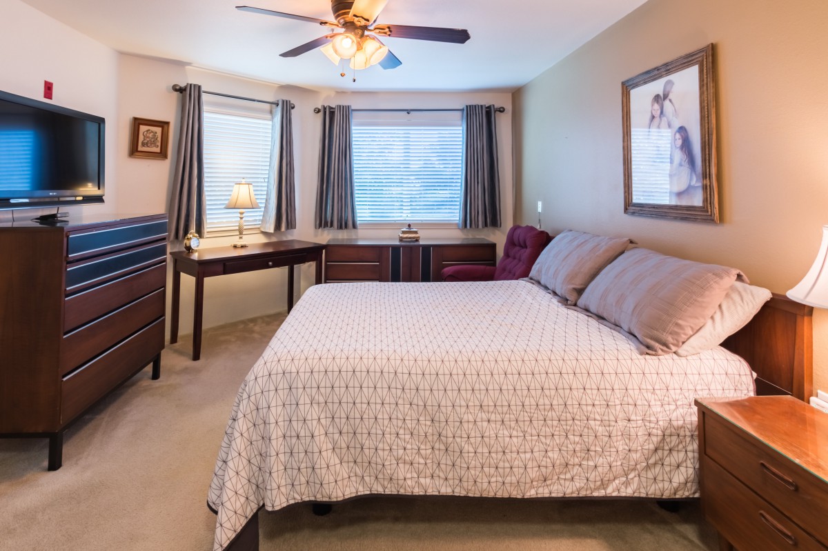 Cozy bedroom with a large bed, ceiling fan, and natural light from the windows.