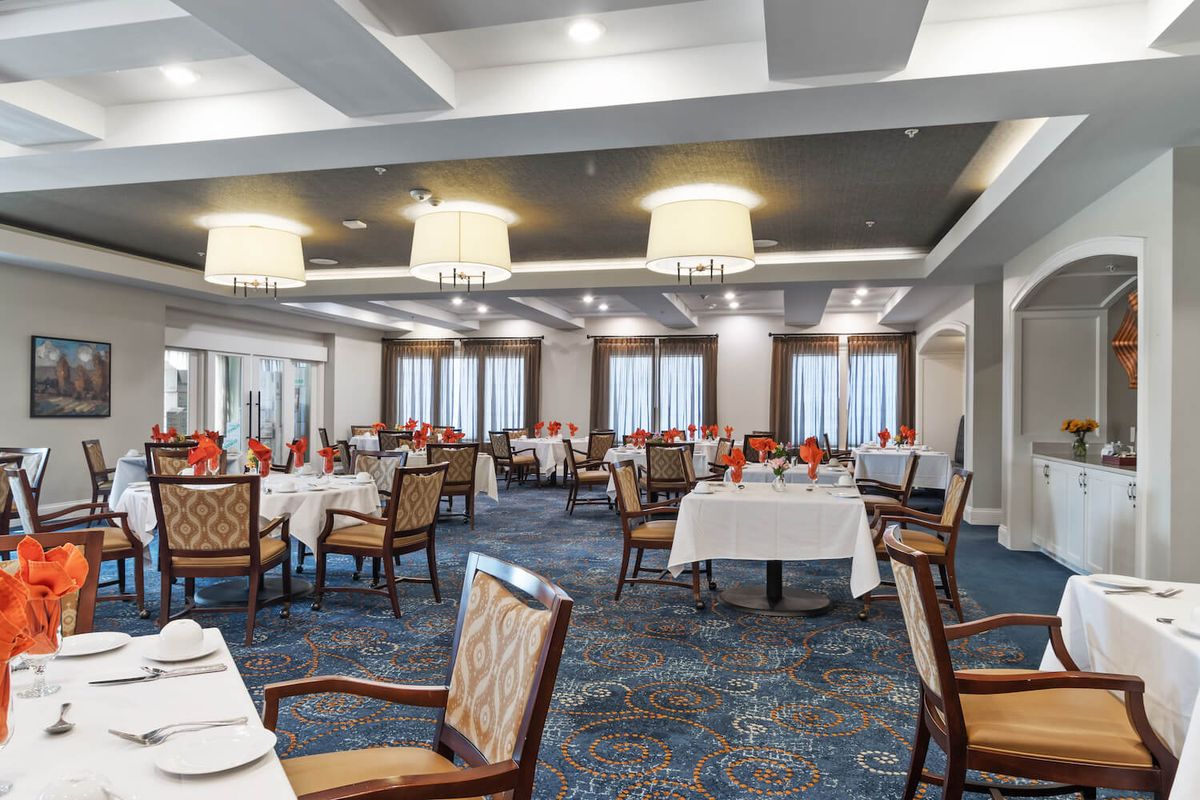 An elegant dining room with neatly arranged tables and chairs, featuring tasteful lighting and decor.