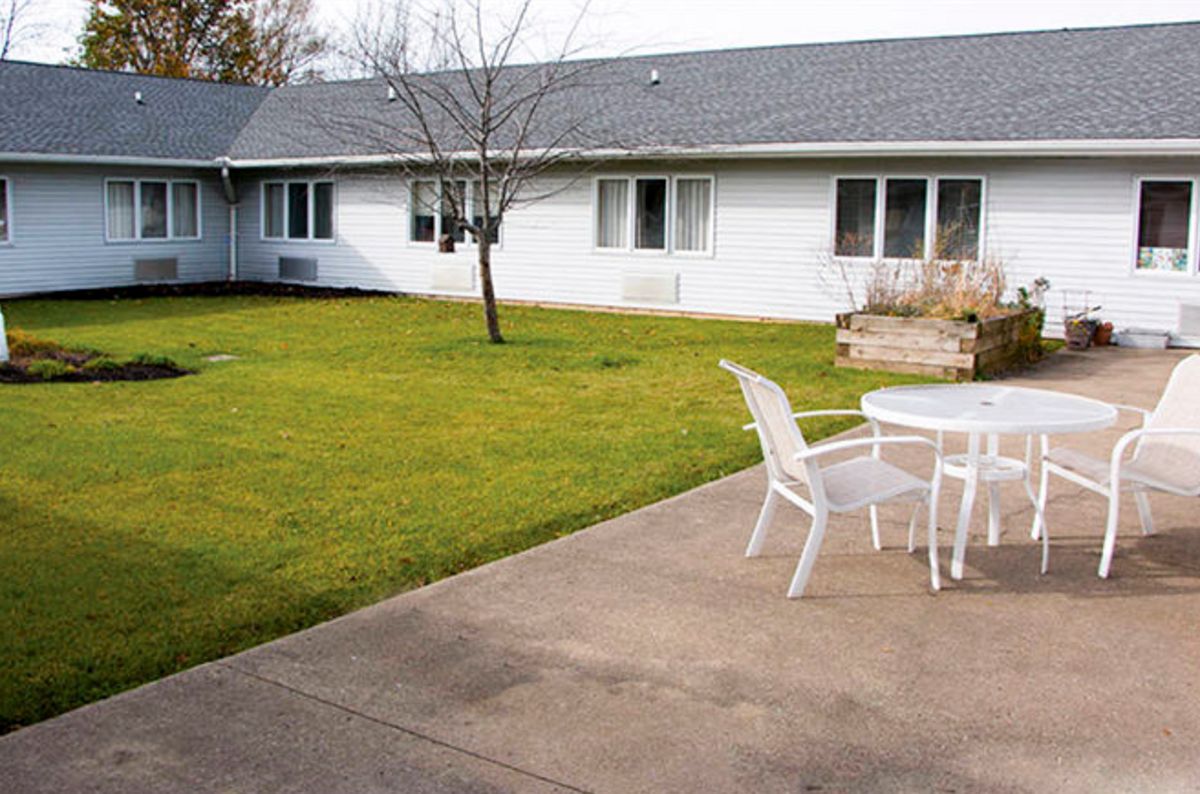 A backyard with a grassy lawn, patio, and outdoor seating.