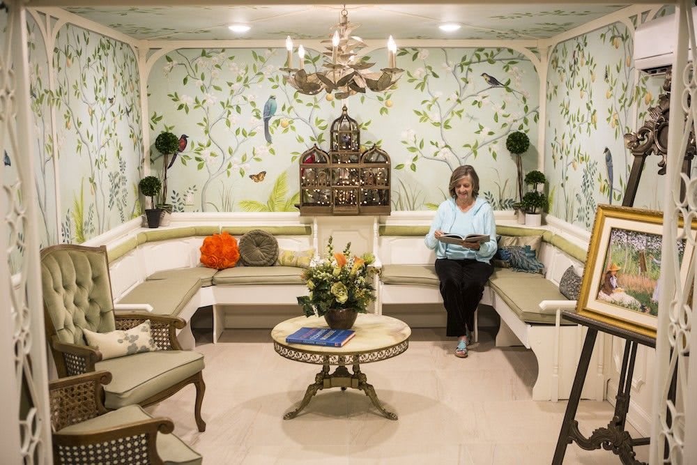 A cozy sitting area with elegant wallpaper and floral decor.