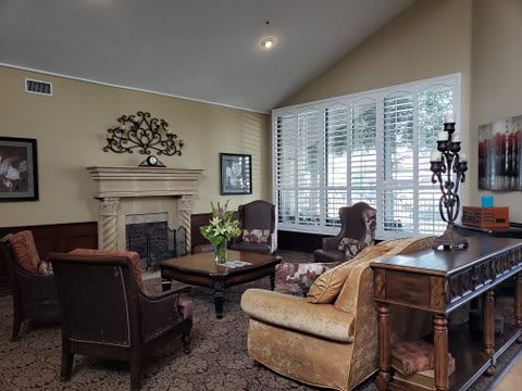 A cozy living room with a fireplace, armchairs, and a coffee table.