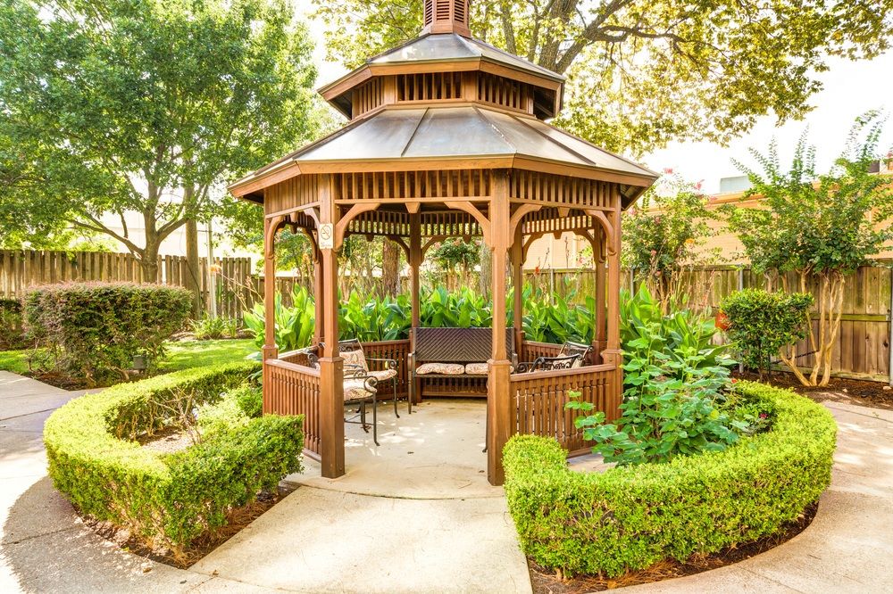 A charming wooden gazebo nestled in a lush garden setting.