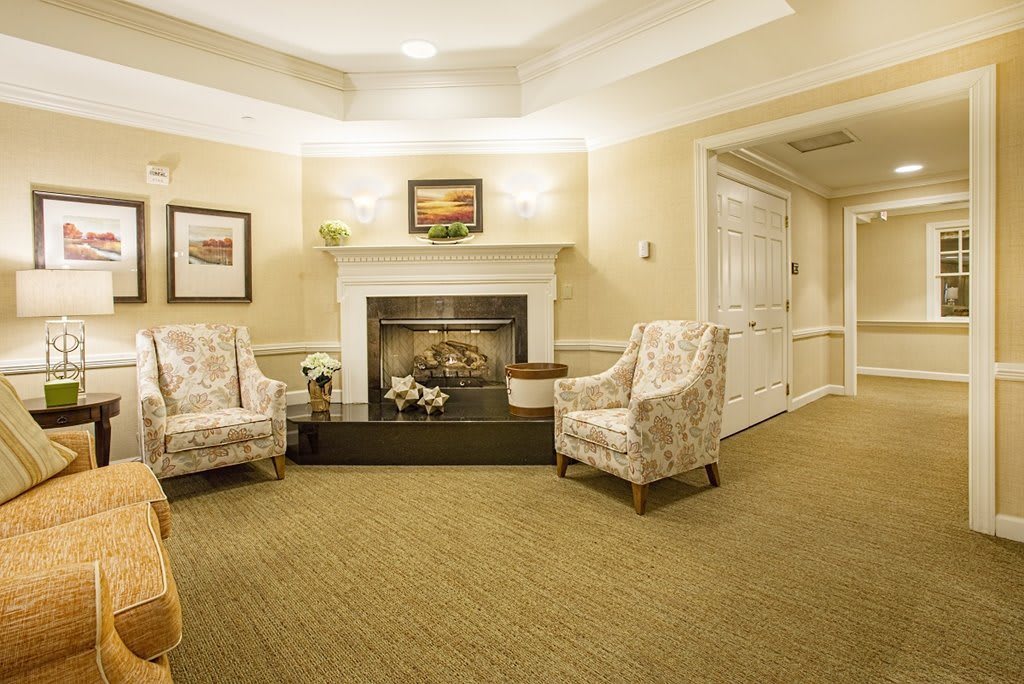 A cozy living room with two armchairs facing a decorated fireplace.