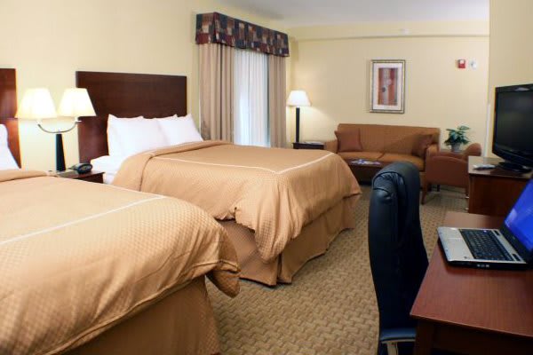 A cozy hotel room with two comfortable double beds and warm lighting.