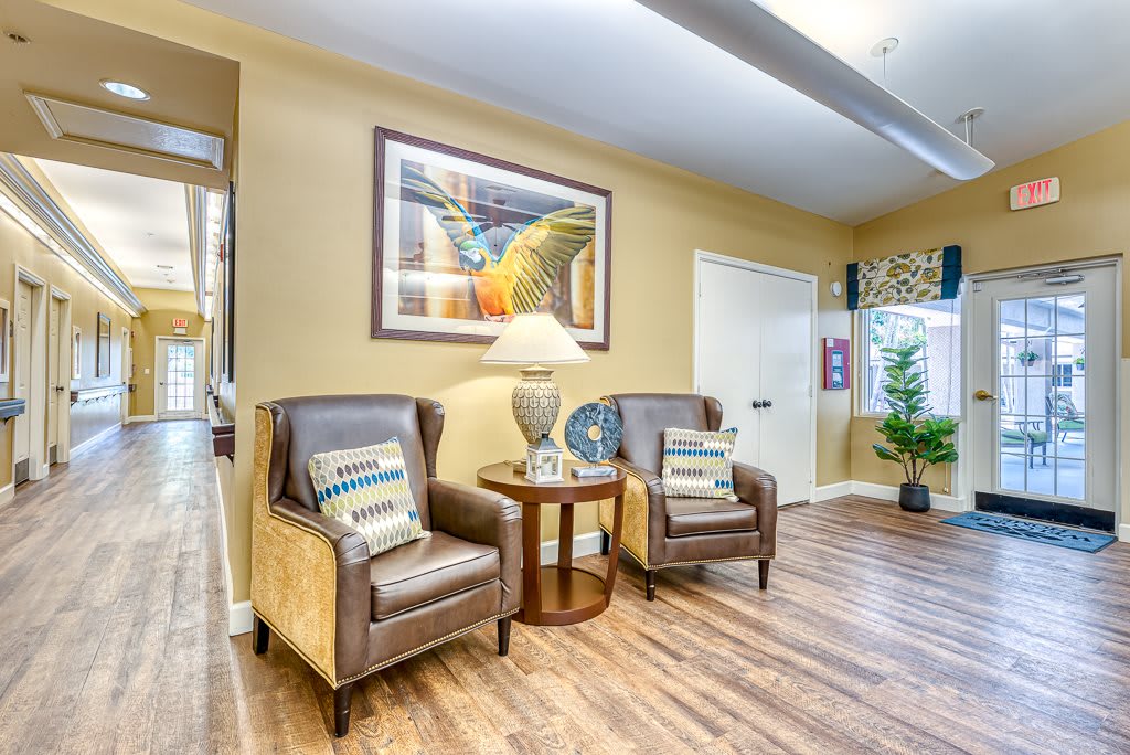 A cozy living room area featuring two leather chairs, a side table with a lamp, and colorful artwork on the wall.