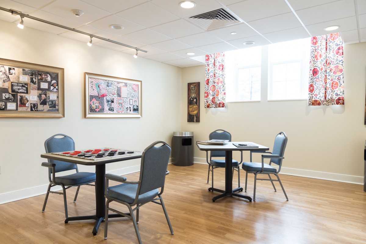 A well-lit meeting room with tables and chairs, decorated with art on the walls.