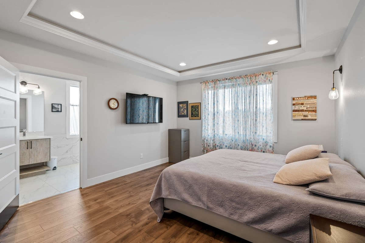 A modern bedroom interior with hardwood flooring, a wall-mounted television, and stylish decor.