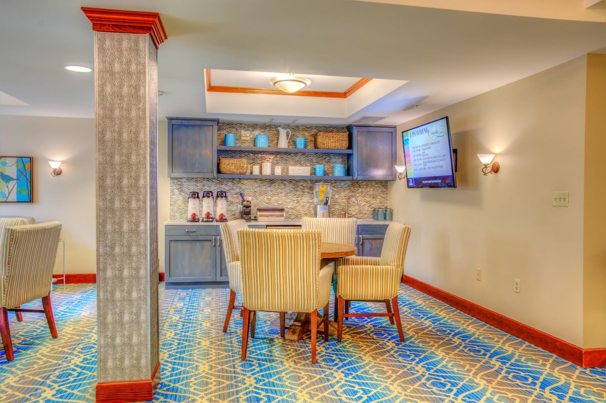 A cozy lounge area with a coffee station, comfortable seating, and a wall-mounted television.
