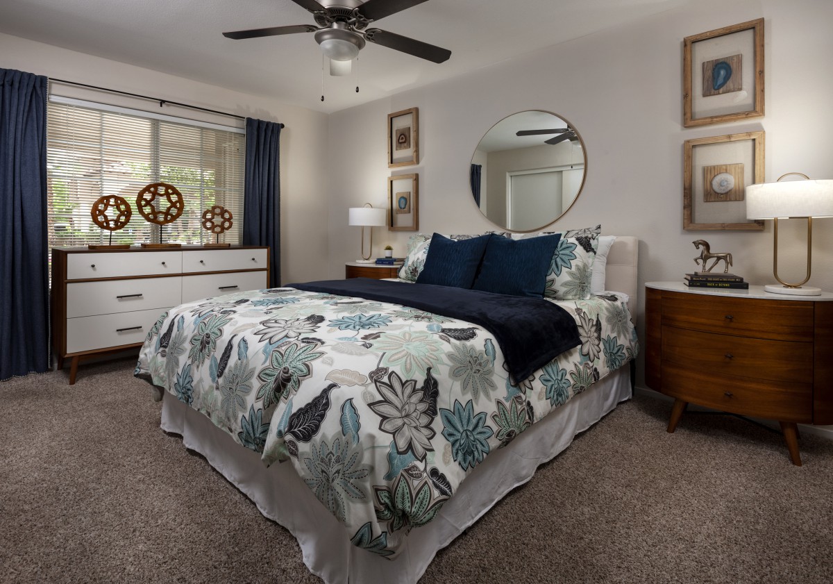 A cozy, well-decorated bedroom with a floral bedspread and modern furnishings.