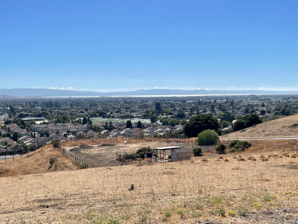 A panoramic view of a suburban area from atop a hill, under a clear blue sky.